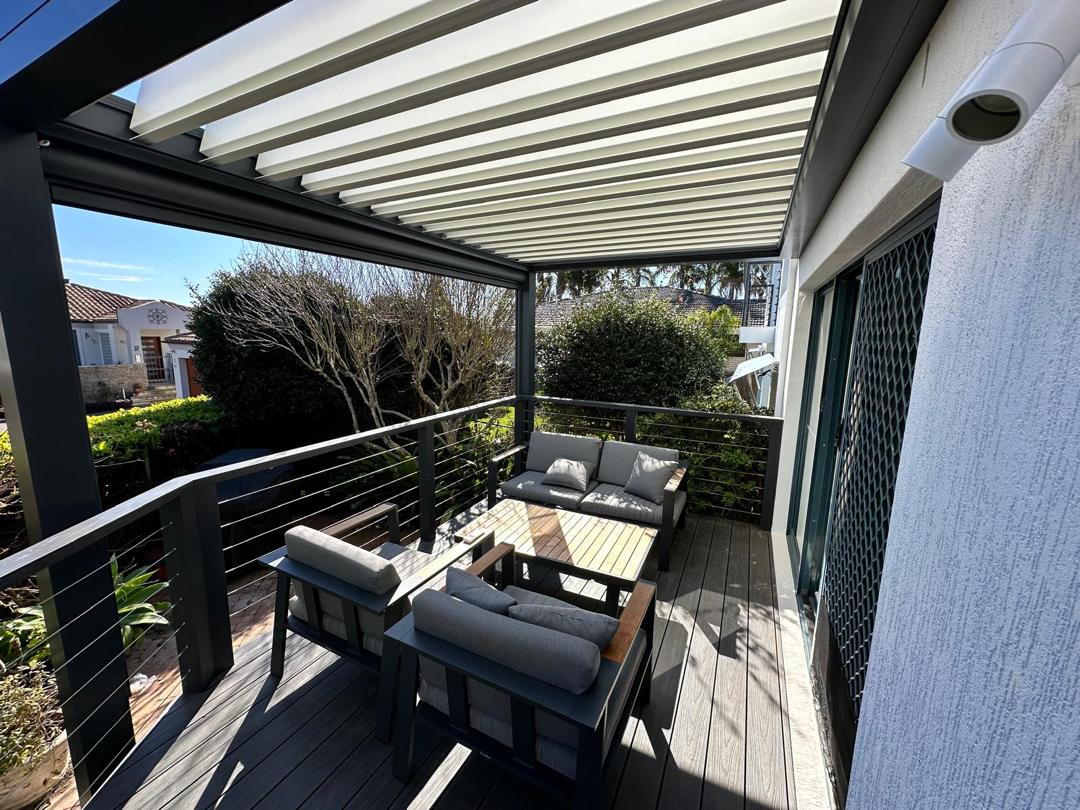 Pérgola Solaz instalada en terraza con sofá exterior y cortina enrollable