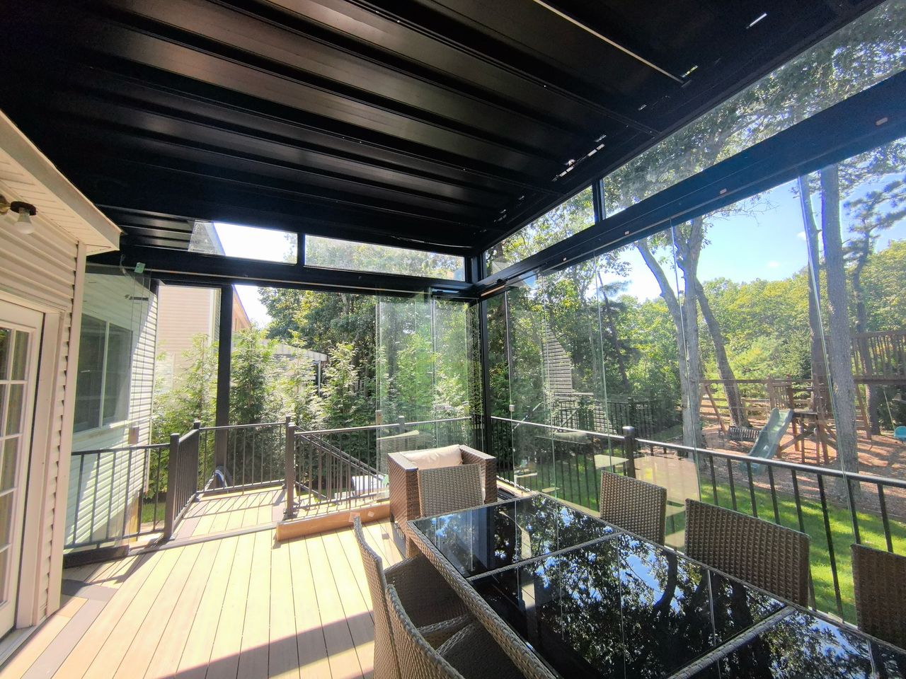 Pérgola Solaz negra con cerramiento de cristal en deck de madera